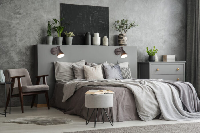 Stylish bedroom interior with bed with blankets and pillows, an